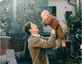 Man lifting baby in a playful manner