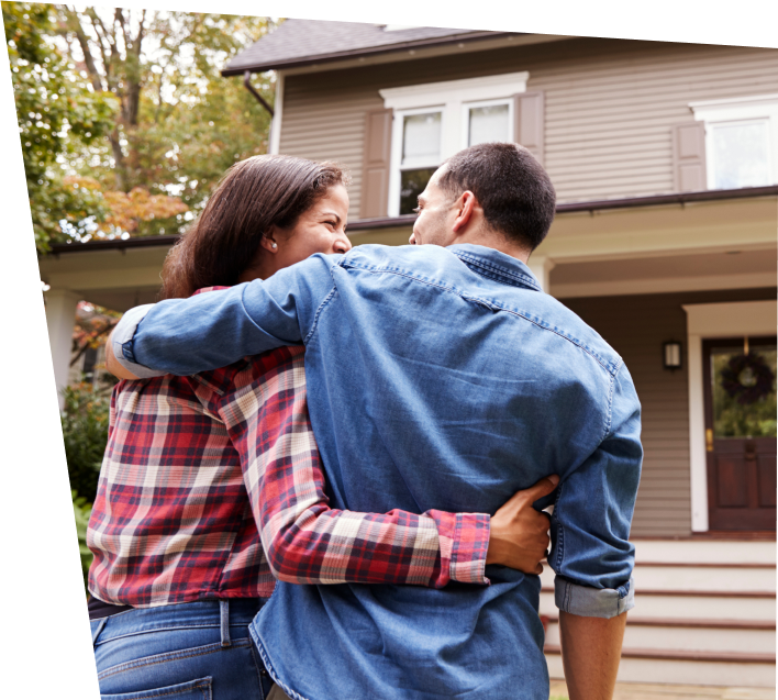 couple smiling in front of house