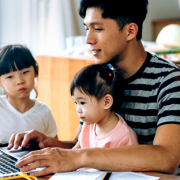 Father using computer to make mortgage payment with daughters watching