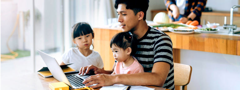 Father making mortgage payment on computer with daughters watching