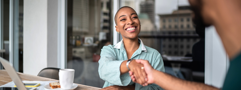 woman shaking hands with a man while sitting at a table