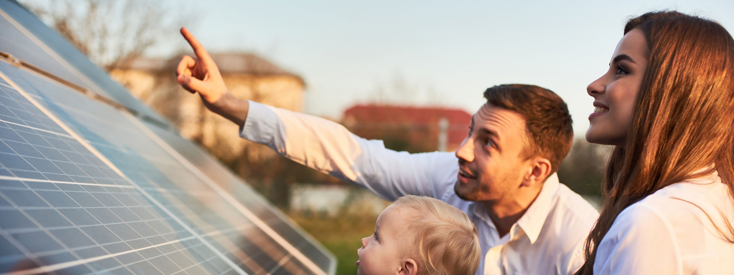 A man, woman, and child looking up at a set of solar panel