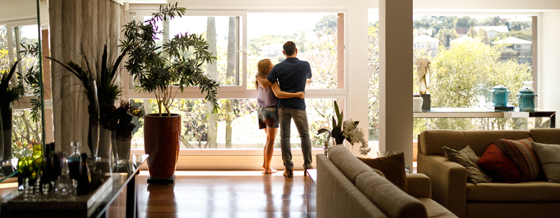 A couple standing in front of a large window in a living room