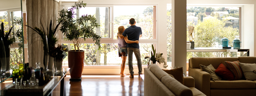 A couple standing in front of a large window in a living room