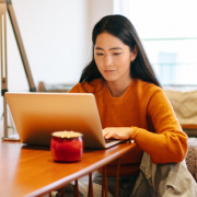 A woman sitting on the floor at a table on a laptop