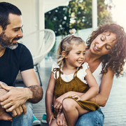 family smiling on front porch of new home