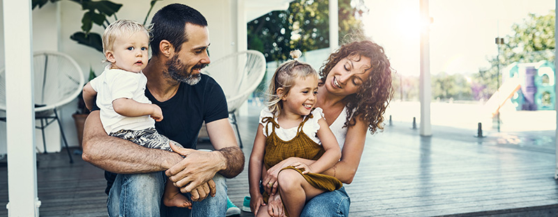 family smiling on front porch of new home