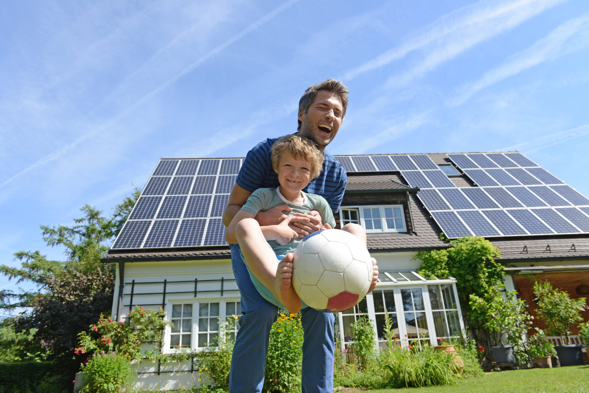 father and son playing ball outside their house