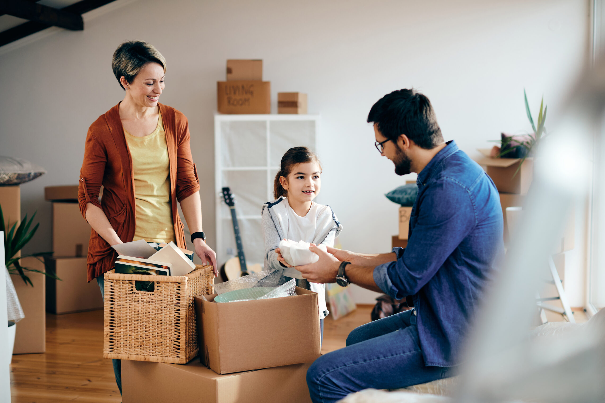 parents and young daughter unpack boxes in new home purchased with no money down