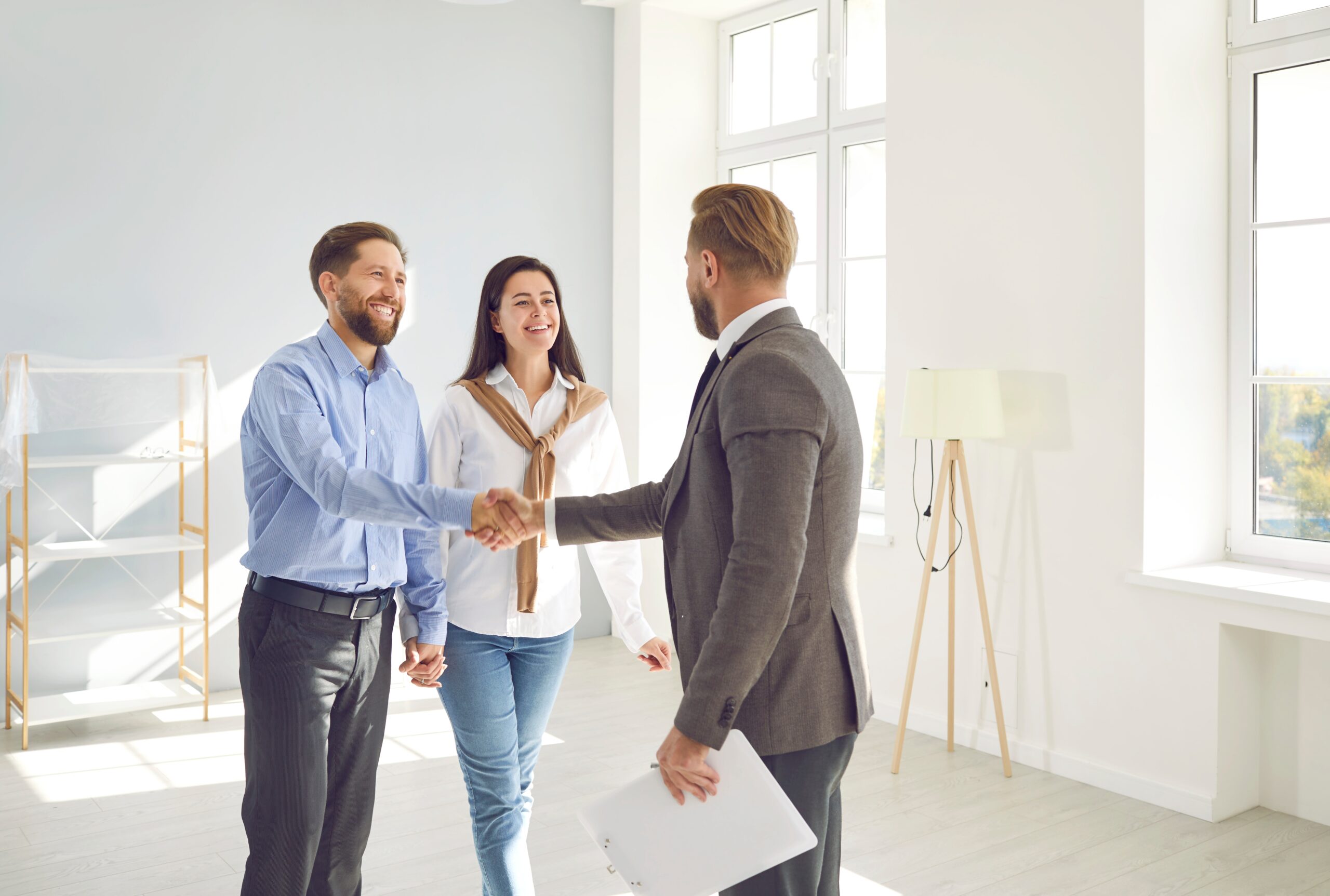 happy couple shakes hands with a realtor after using a home loan to buy an investment property