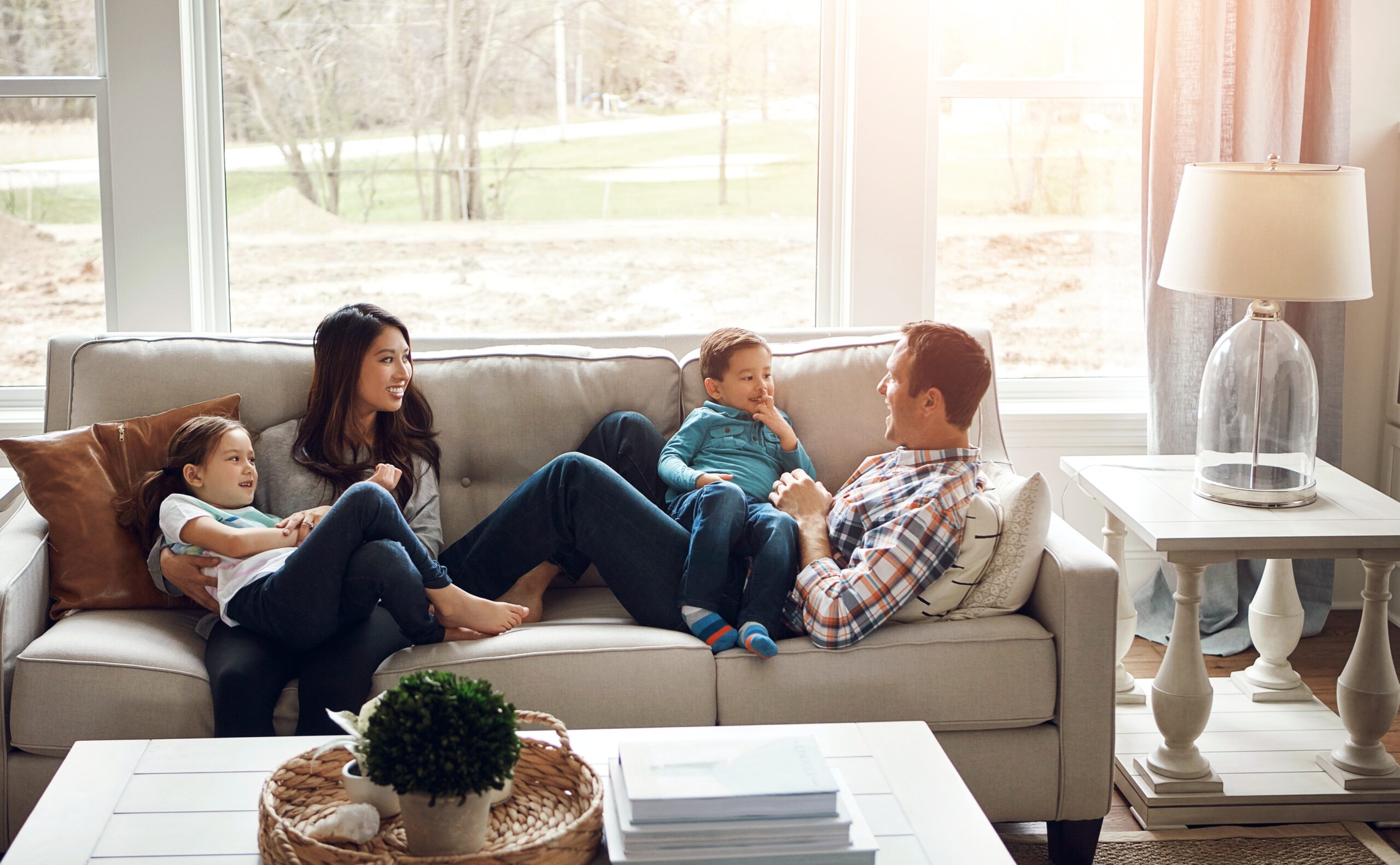 A couple and their two young children relax together on the couch in their new home.