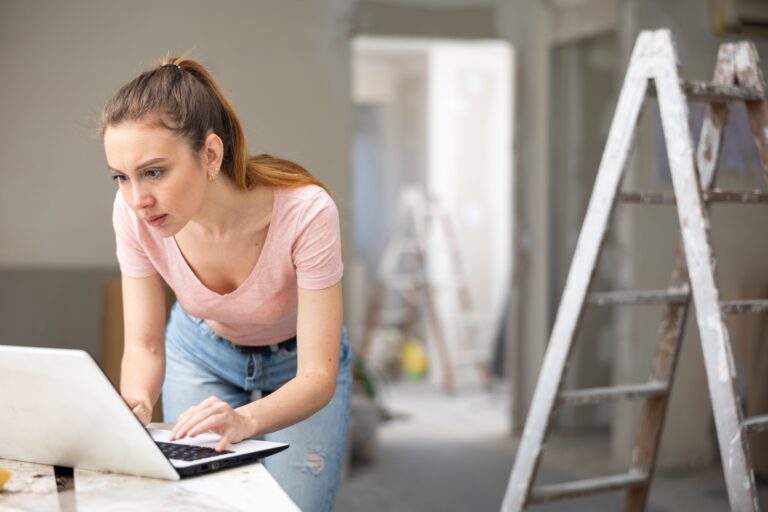 A woman checks her account on a laptop while she takes a break from managing her kitchen renovation.