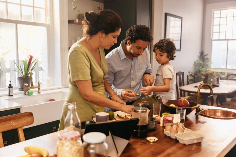 husband, wife, and child make breakfast at the kitchen counter
