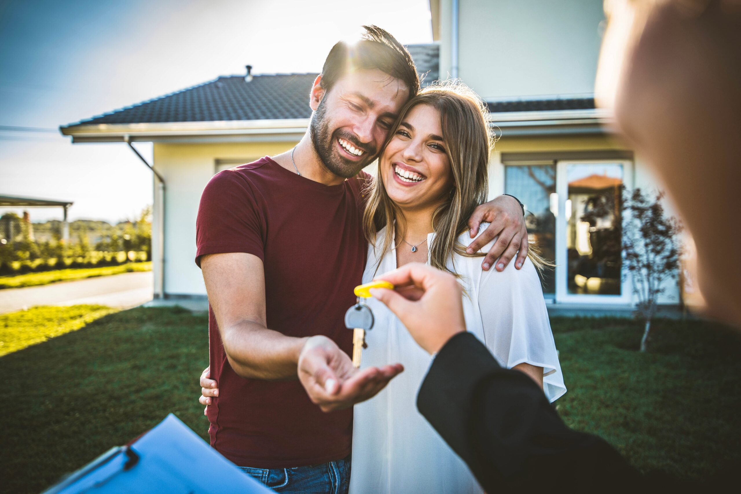 A happy young couple smiles while accepting the keys to their first home.