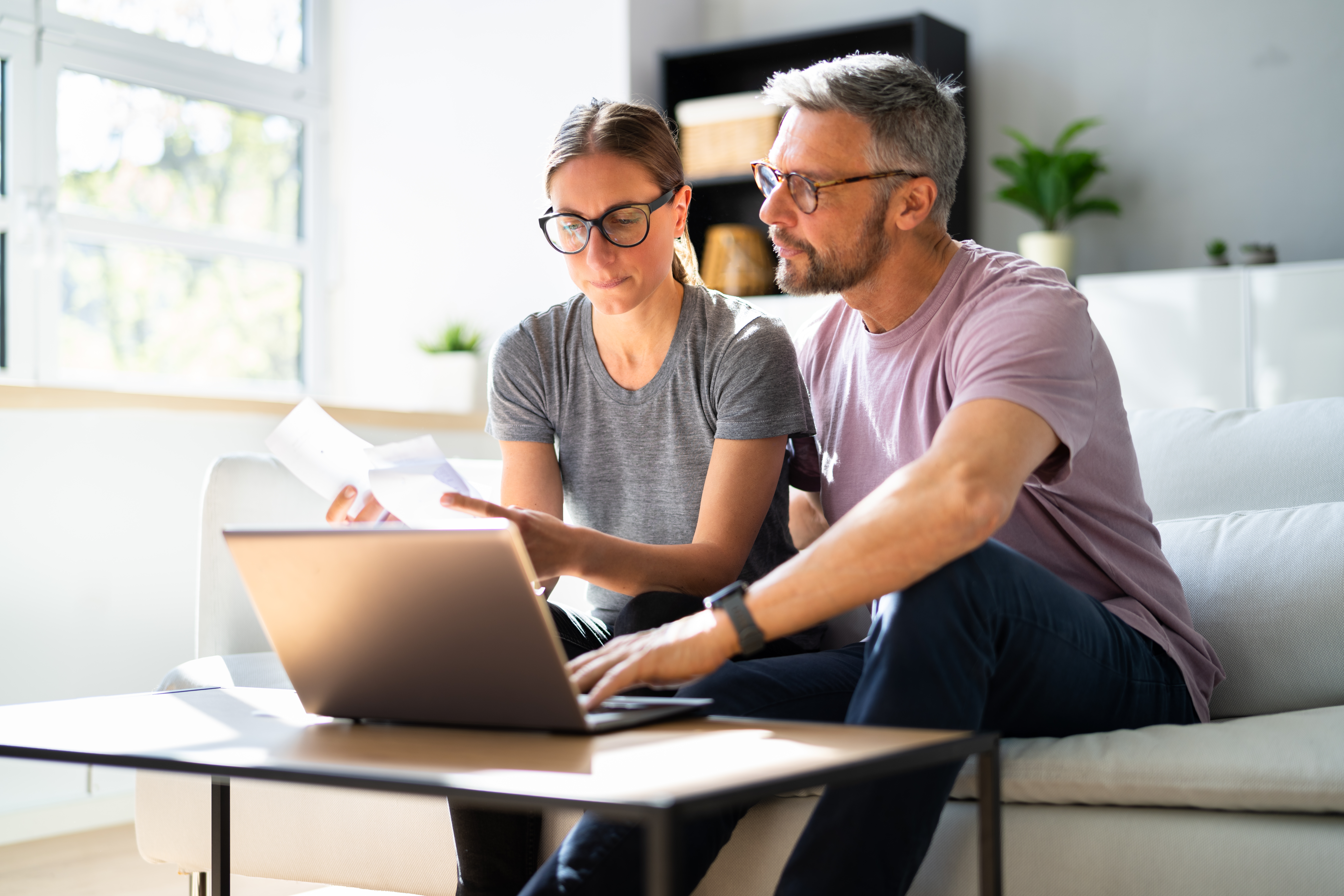 couple on the couch use a computer to calculate a break-even point in their mortgage refinance